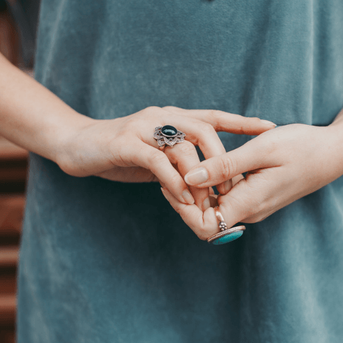 Statement Rings: Close-up of hands wearing two large silver rings.