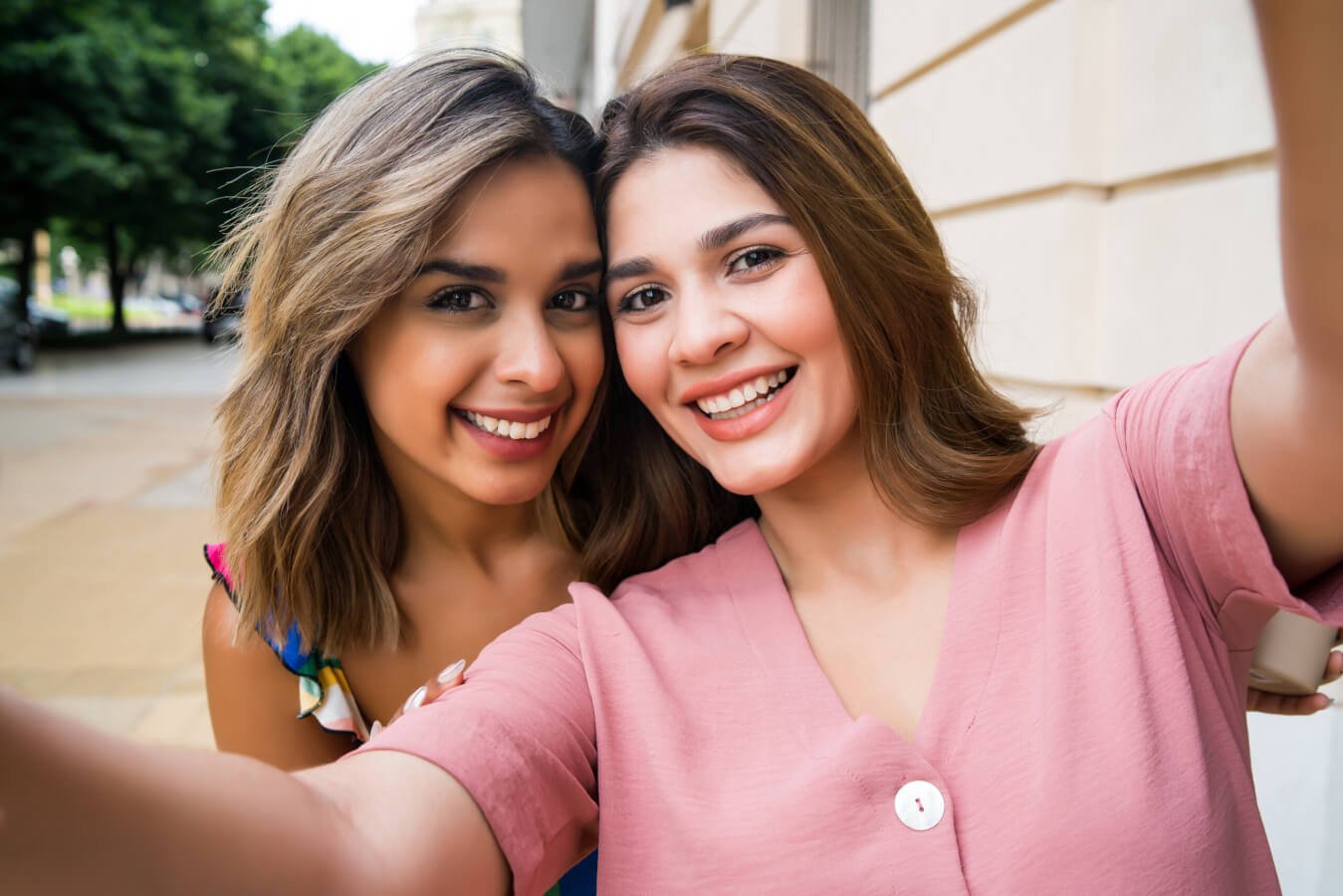 Portrait of two young friends taking a selfie while standing outdoors on the street. Urban concept.