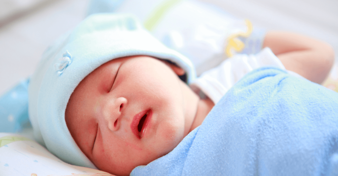 Newborn baby sleeping in a blue hat and blanket