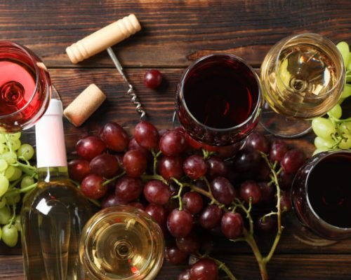 Flat lay. Grapes, corkscrew, bottles and glasses with wine on wooden background
