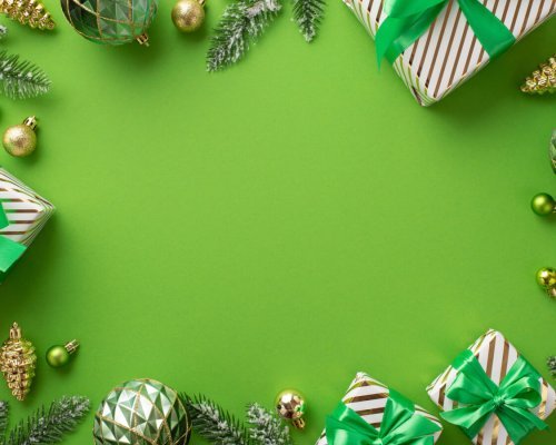 Christmas concept. Top view photo of gift boxes with bows gold and green baubles pine cone ornaments and fir branches in hoarfrost on isolated green background with empty space in the middle